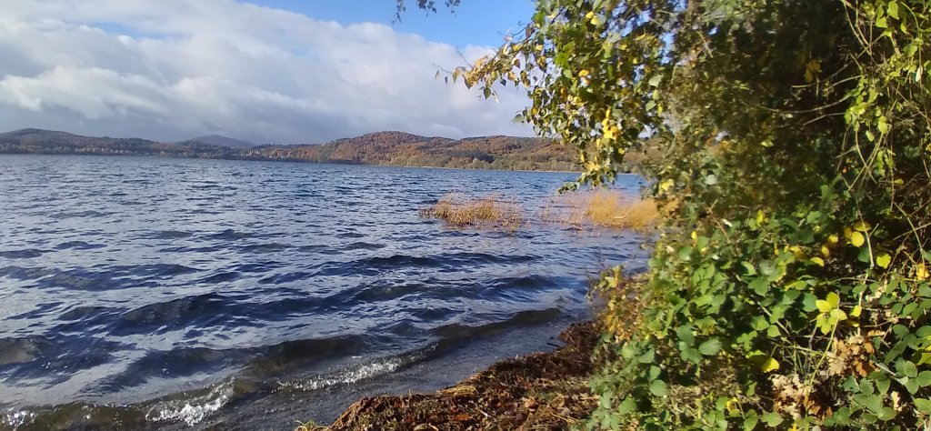 Wellengang von links, Ufer rechts, im Hintergrund in der Ferne das hügelige Ufer. Herbstsonne.